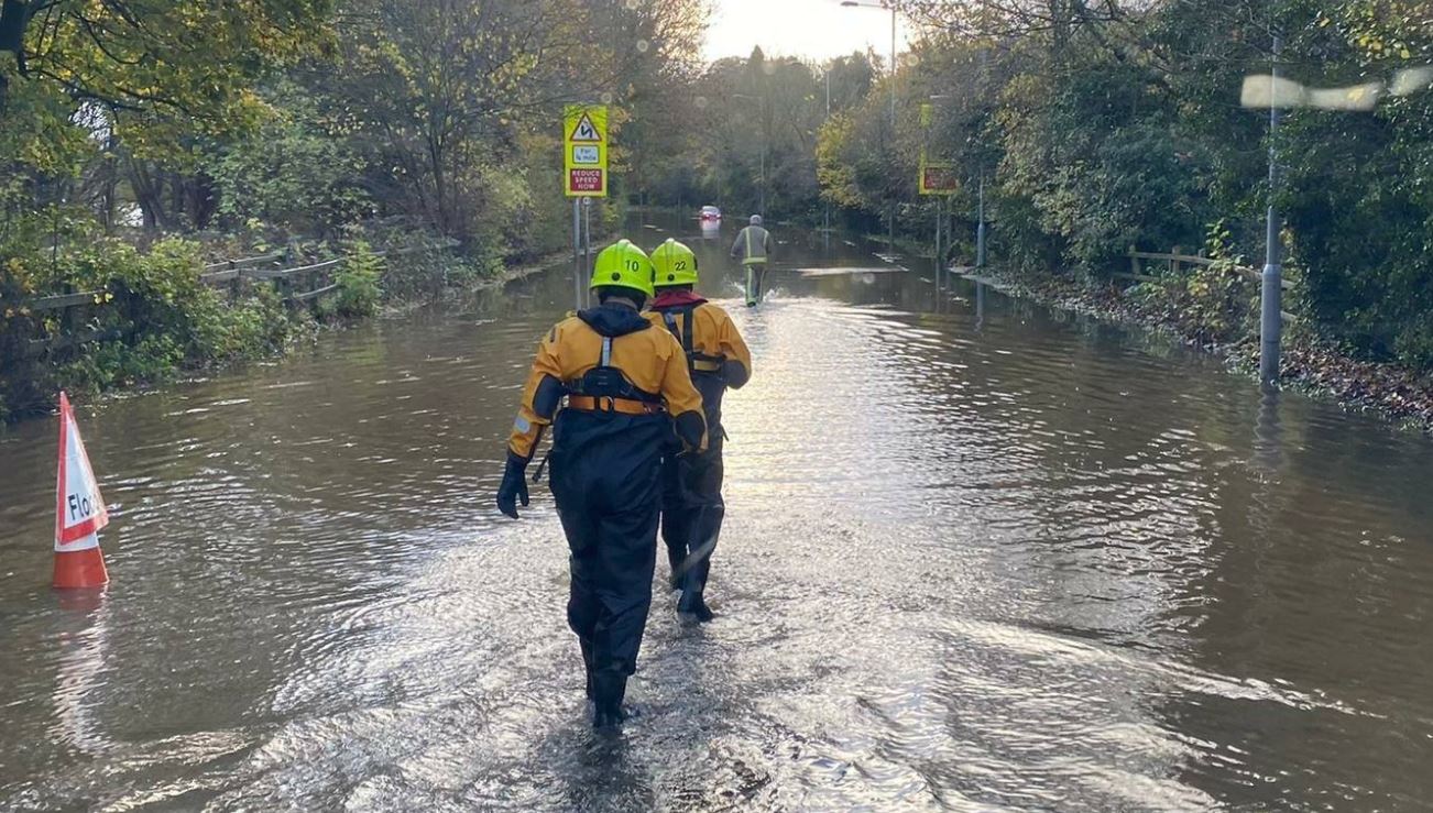 Firefighters wading through flood water. 