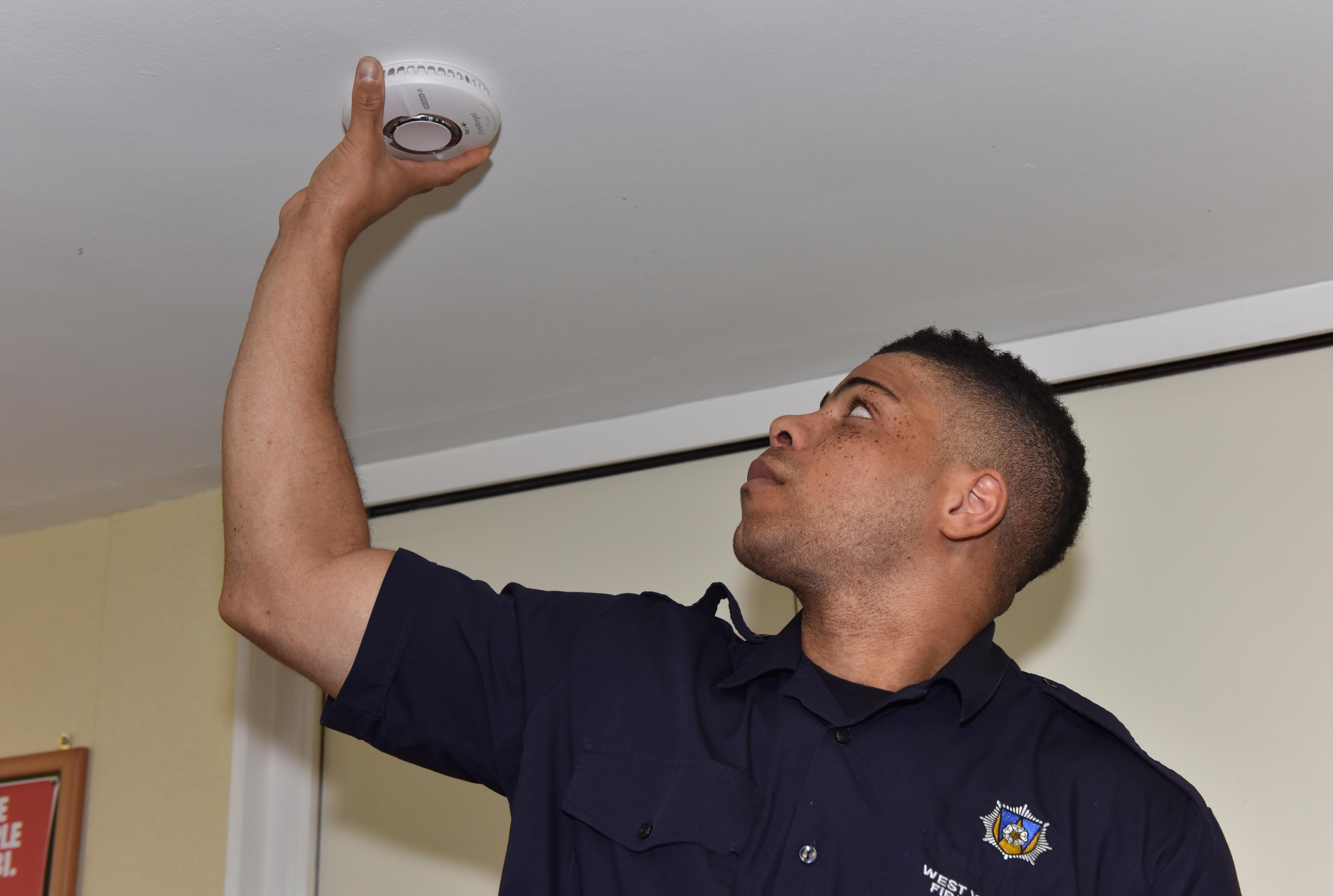 Firefighter fitting smoke alarm. 