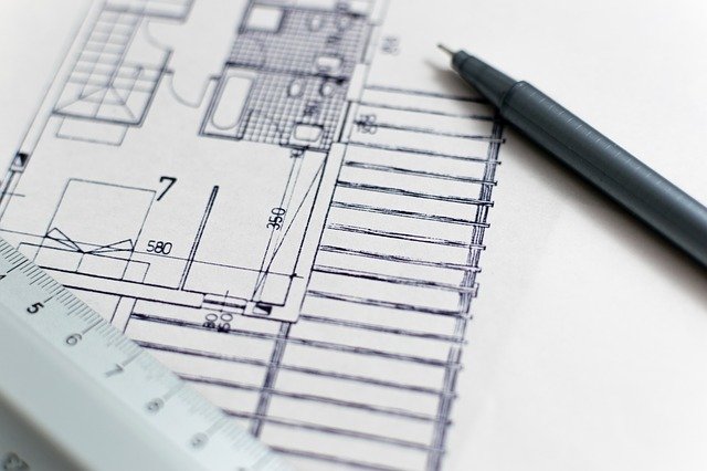 Pen and ruler on paper with building plans drawn on.