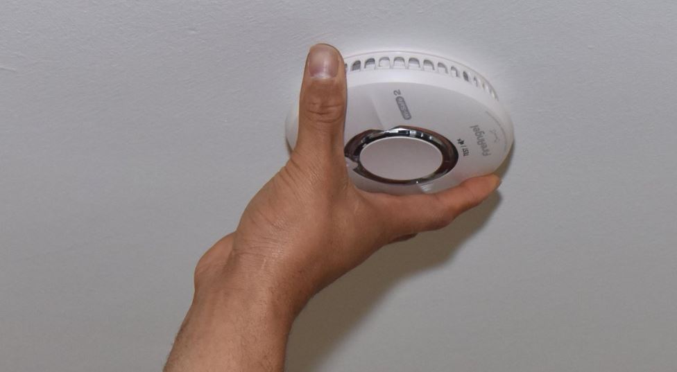 Hand fitting a smoke alarm. 