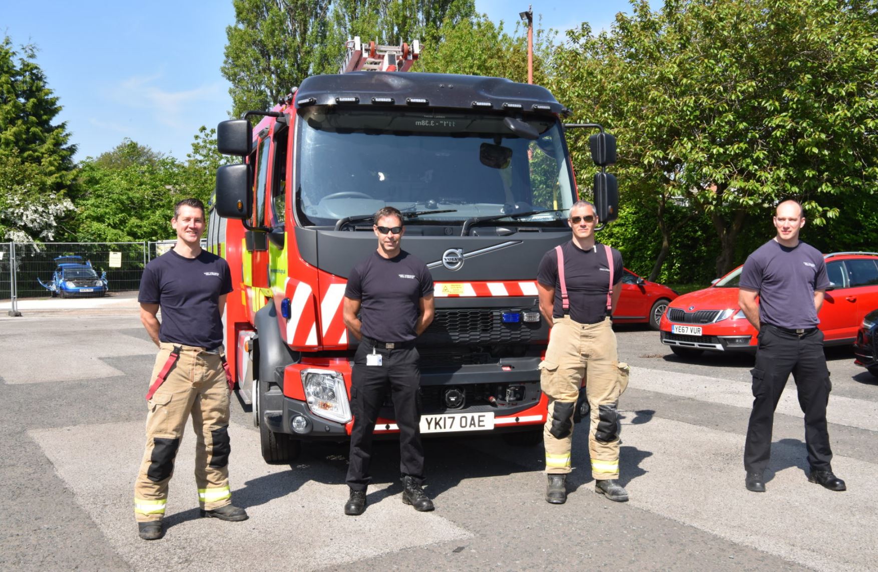 Firefighters stood in front of a Fire engine in car park. 