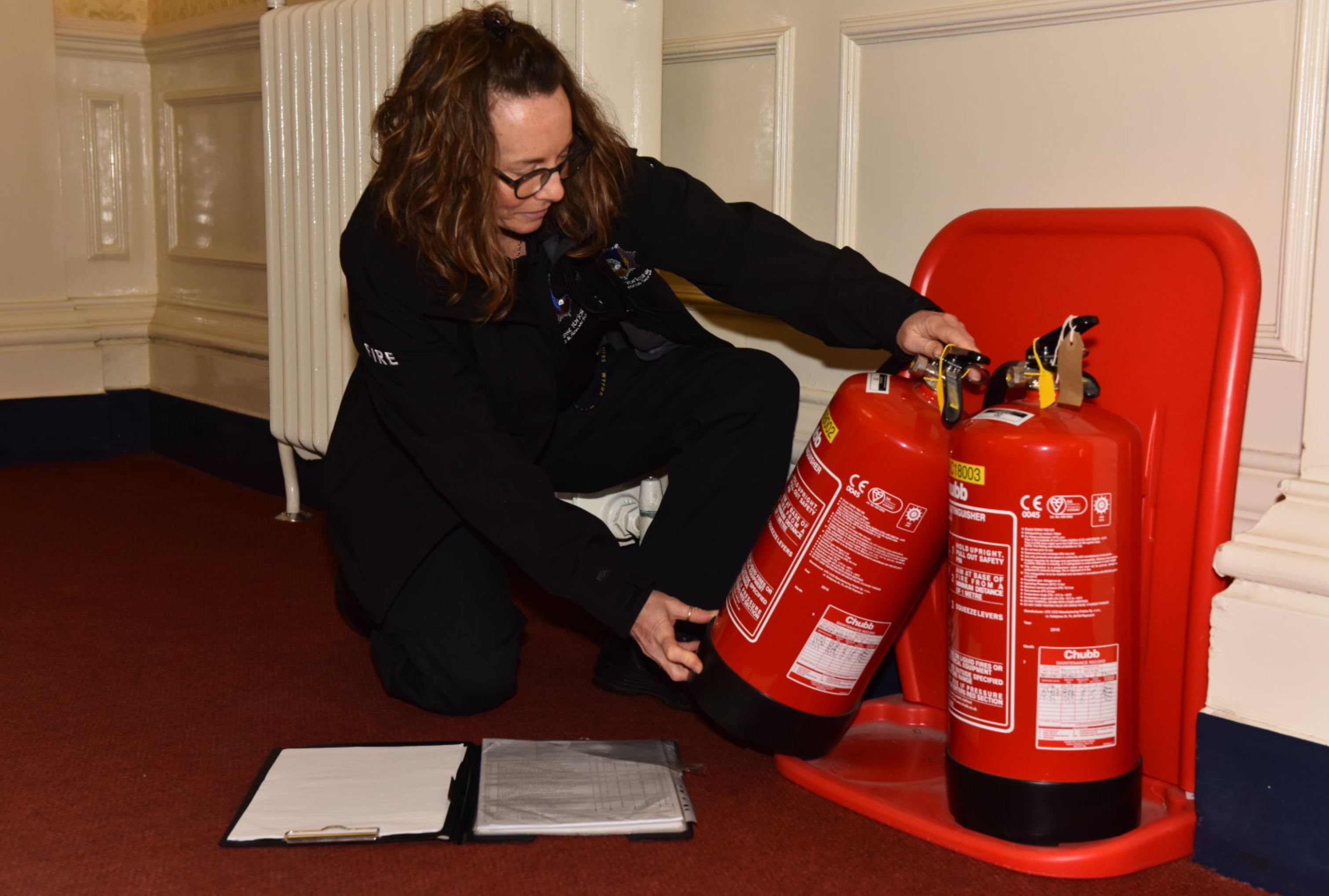 female WYFRS worker checking fire extinguisher 