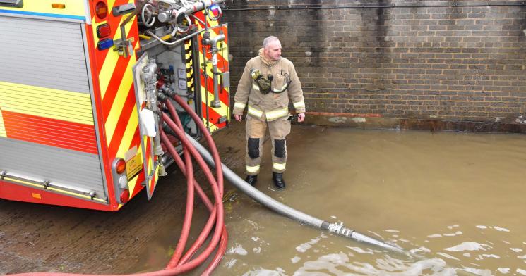 Firefighter with Fire Engine, helping to pump water during a flood. 